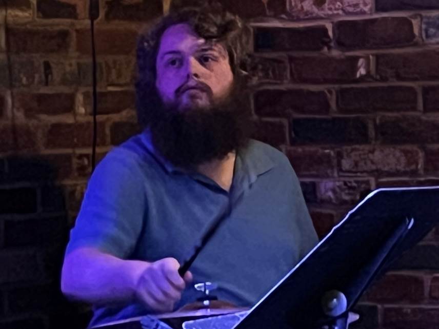 A person with a beard playing a musical instrument

Description automatically generated