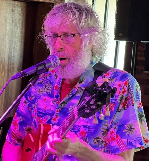 A person with a guitar and a microphone

Description automatically generated