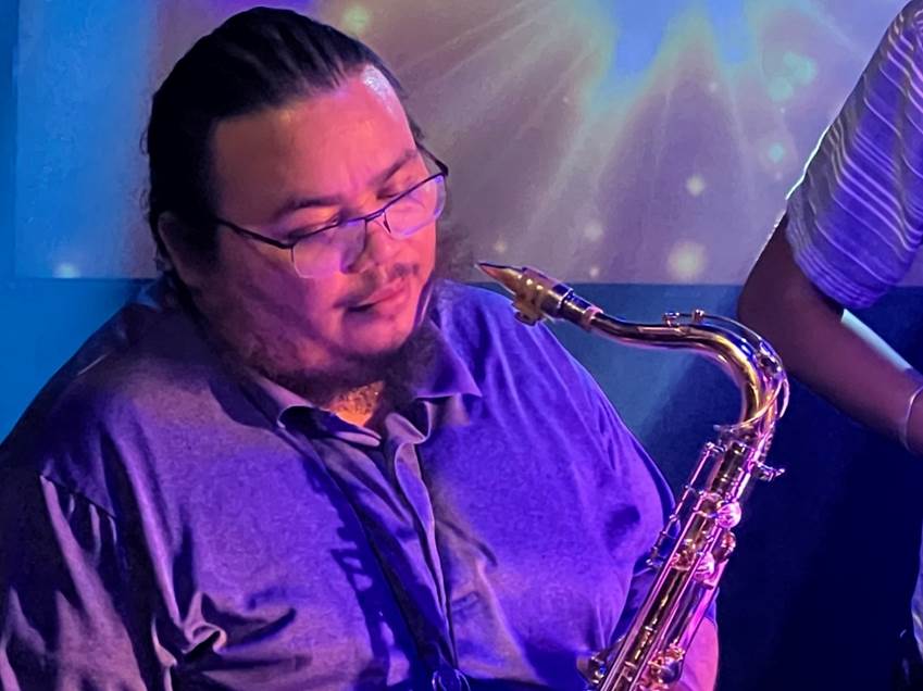 A person sitting with a saxophone

Description automatically generated
